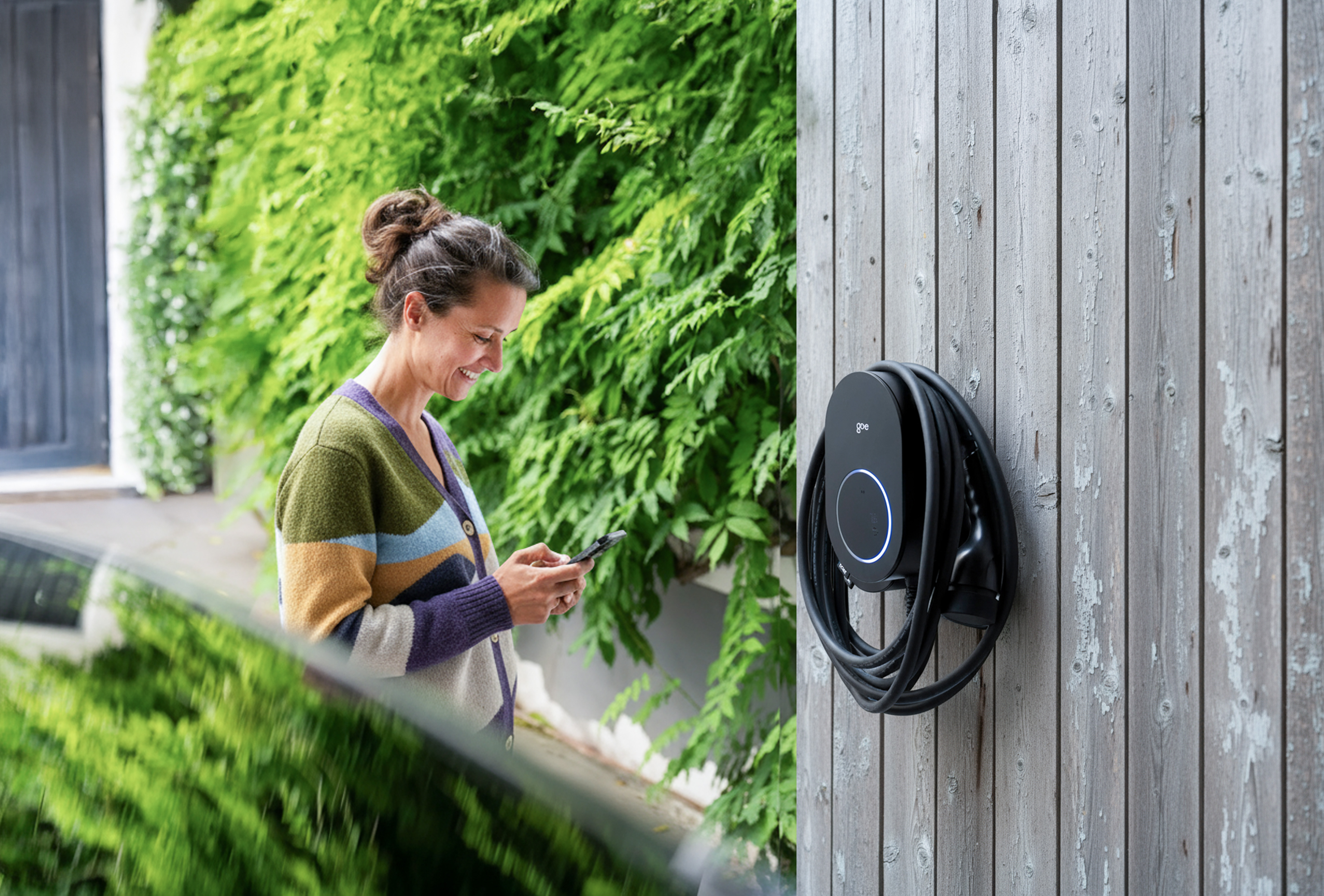 Kvinde styrer hjemmelader med app — go-e Charger Gemini flex 2.0 monteret på væg